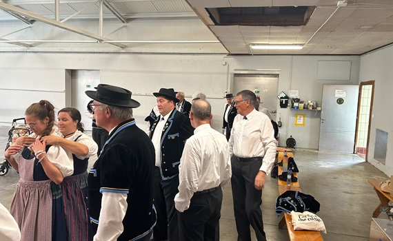 Eine Gruppe von Menschen in traditioneller Kleidung steht in einem Raum und bereitet sich auf eine Veranstaltung vor.